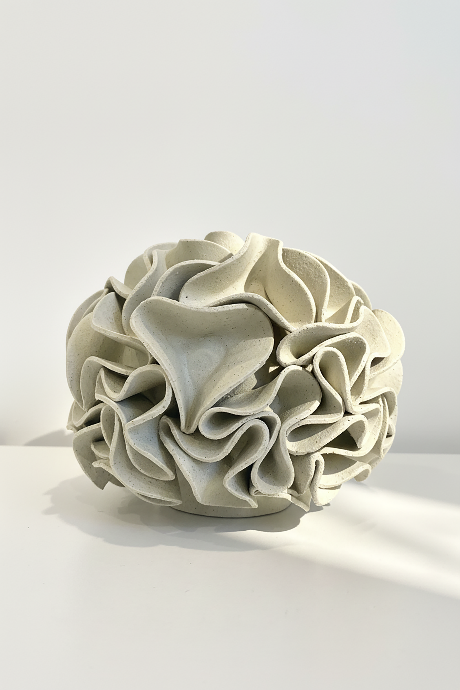 Decorative ceramic vase with ruffled texture on natural white clay