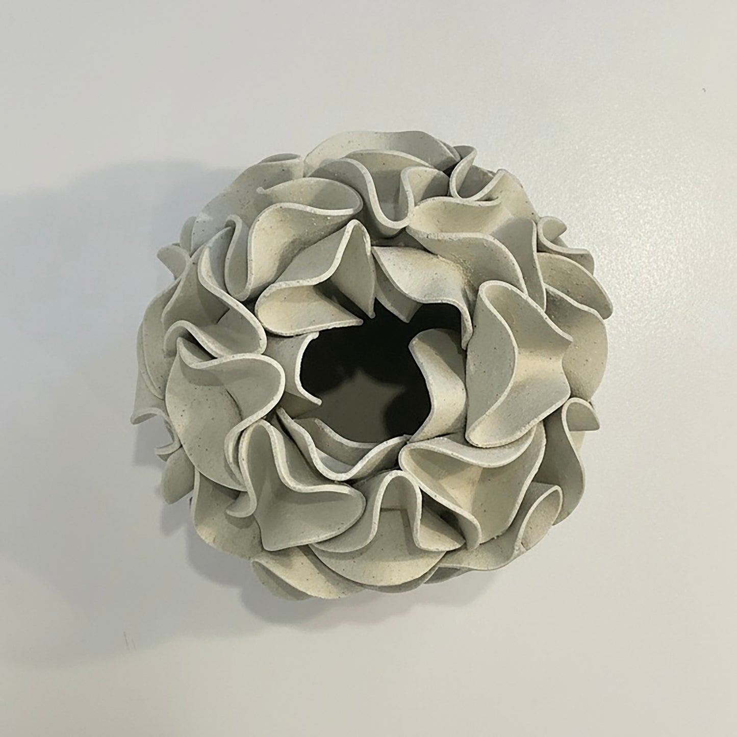 Decorative ceramic vase with ruffled texture on natural white clay - looking down