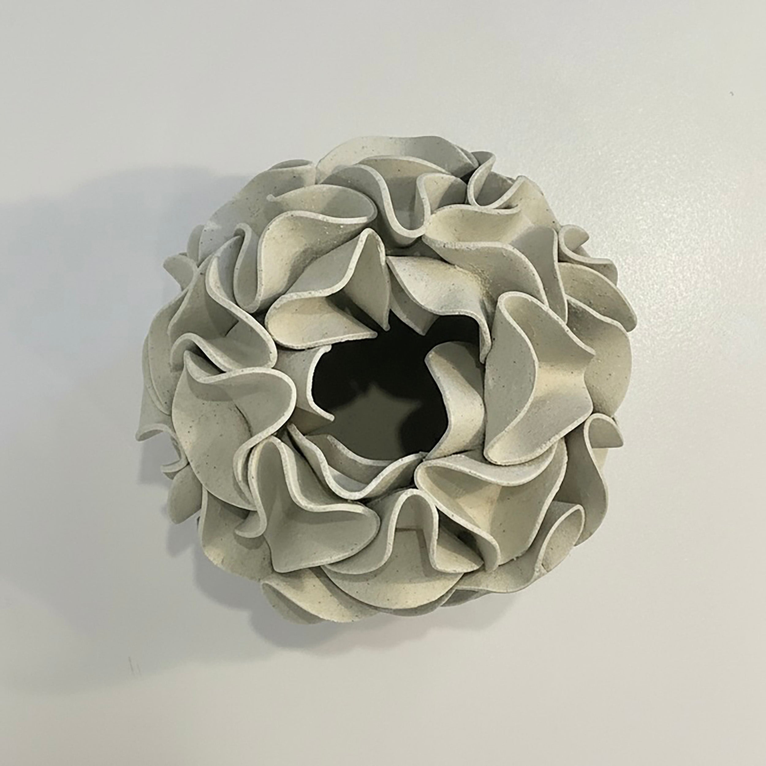 Decorative ceramic vase with ruffled texture on natural white clay - looking down