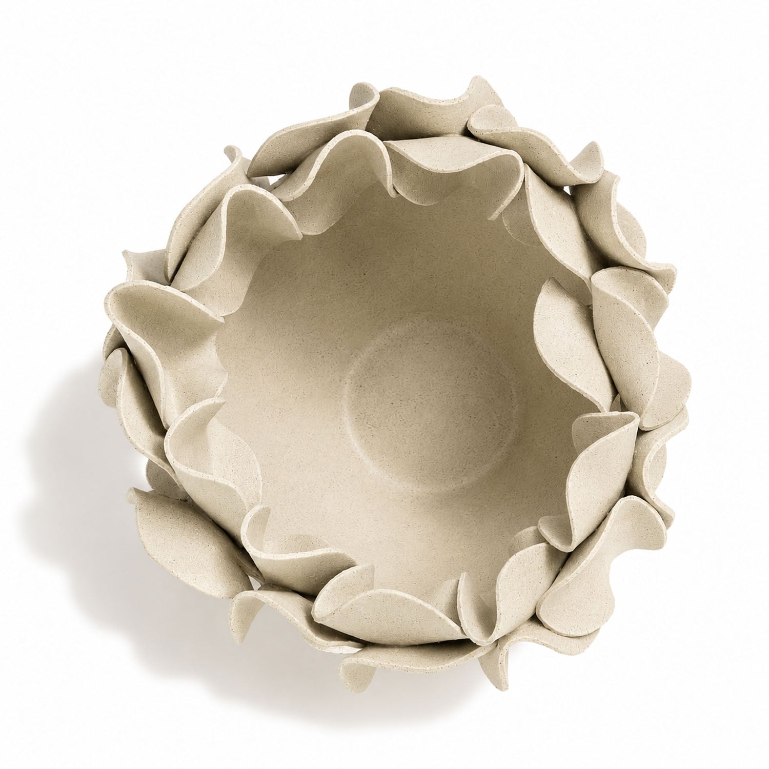 A top-down view of a beige ceramic bowl with a decorative, layered petal-like rim, set against a plain white background with a soft shadow.