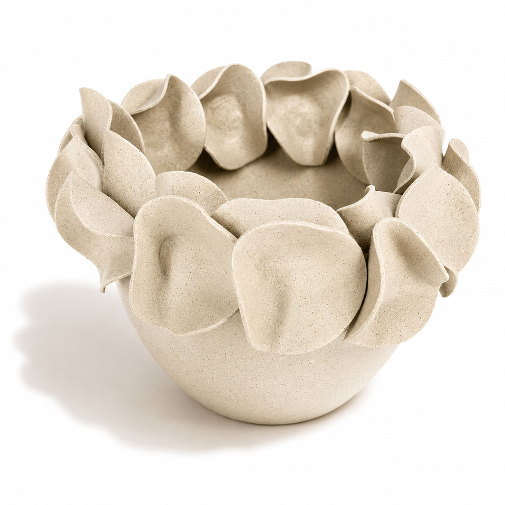 A light beige speckled ceramic planter with a wide rim made of overlapping petal-like protrusions. By Polly Barton.