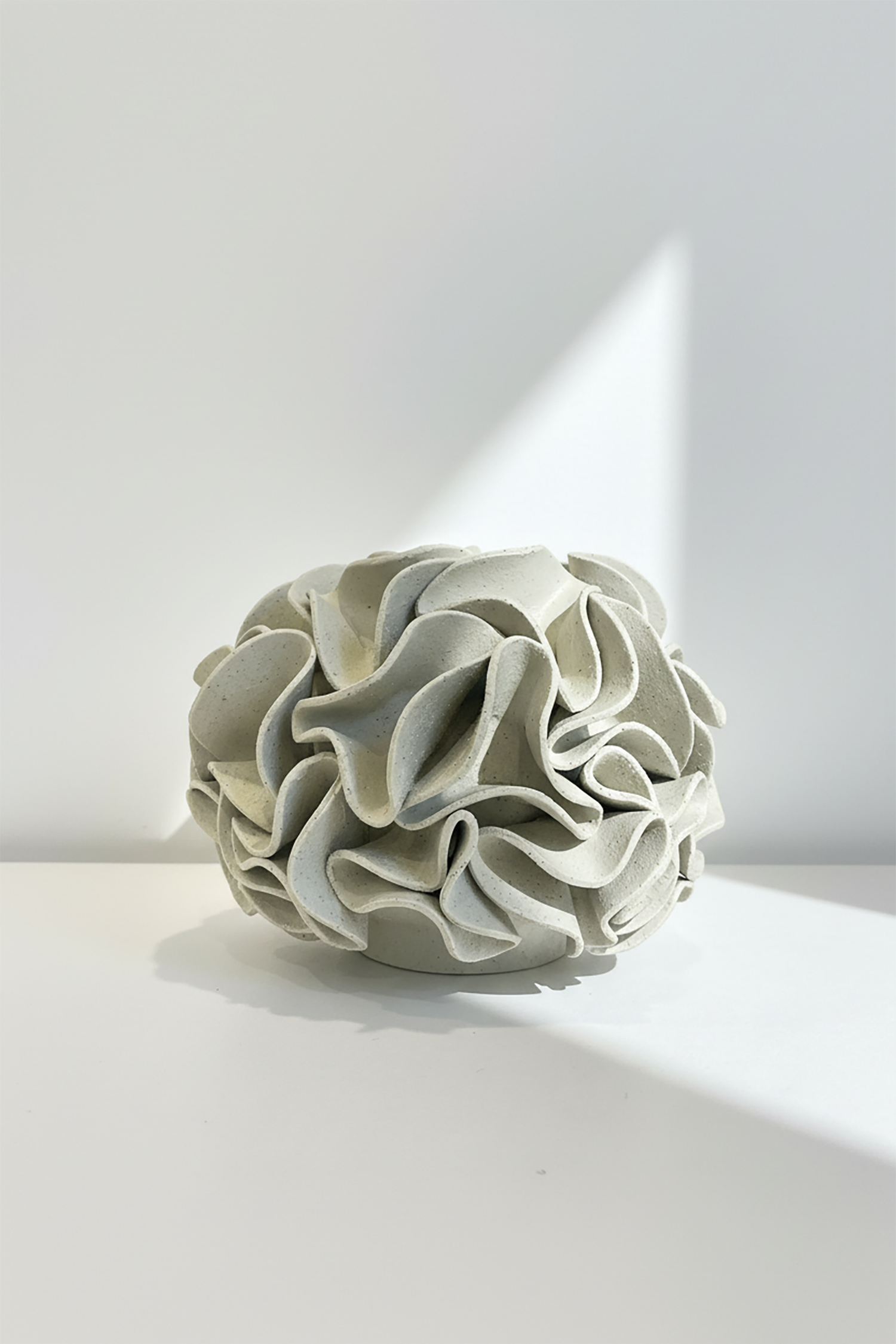 Decorative ceramic vase with ruffled folds on natural white clay